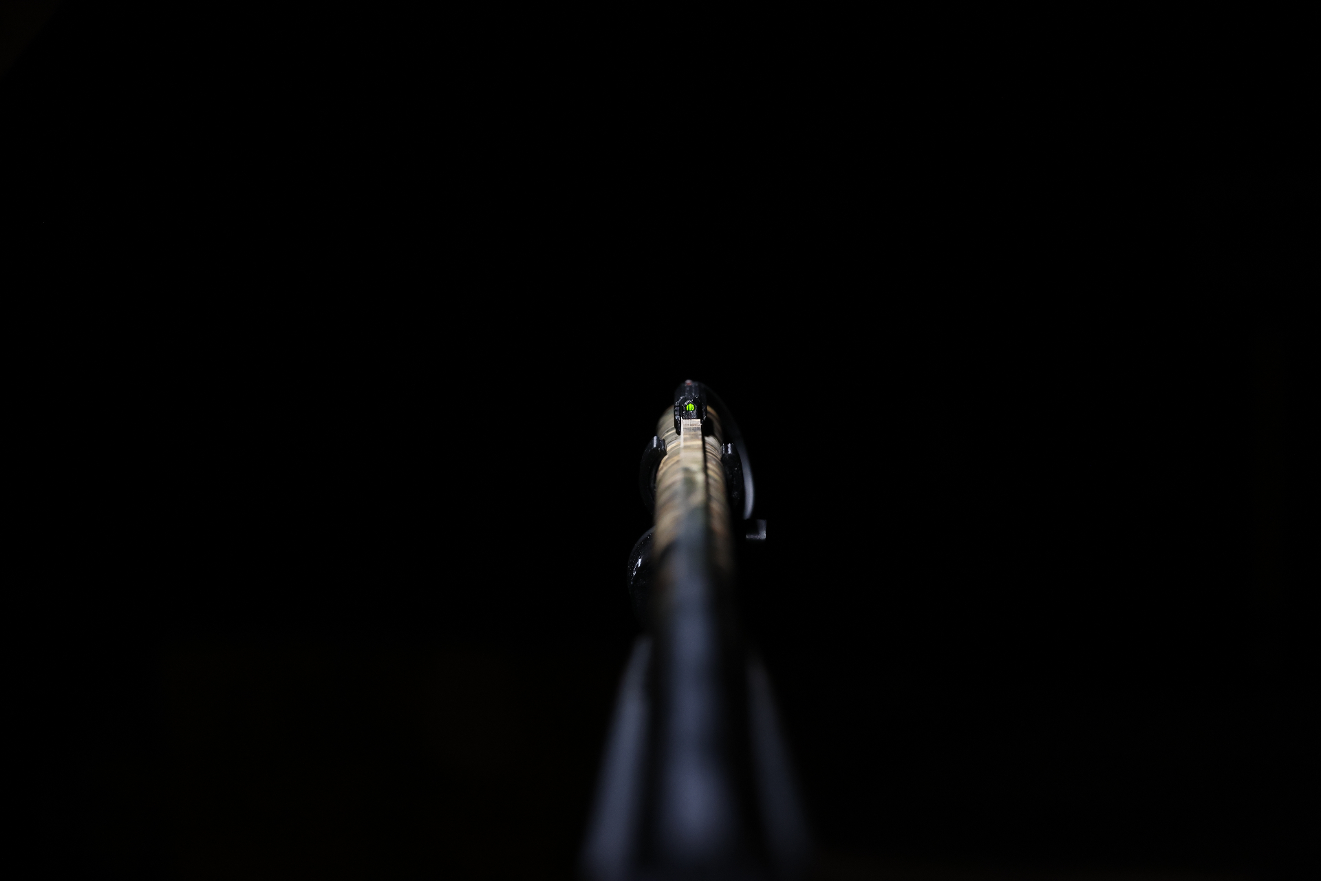 NiteDot bead glowing in complete darkness along a shotgun barrel